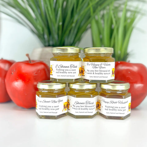 2 oz honey Rosh Hashanah new year favors on hexagon jars with gold lid with personalized honey-themed labels. Multiple titles shown including To a Happy and Healthy New Year, L'Shana Tovah, Happy Rosh Hashanah, Shana Tovah, and Have a Sweet New Year.