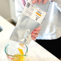 Honey being poured from Mylar pouch into measuring cup